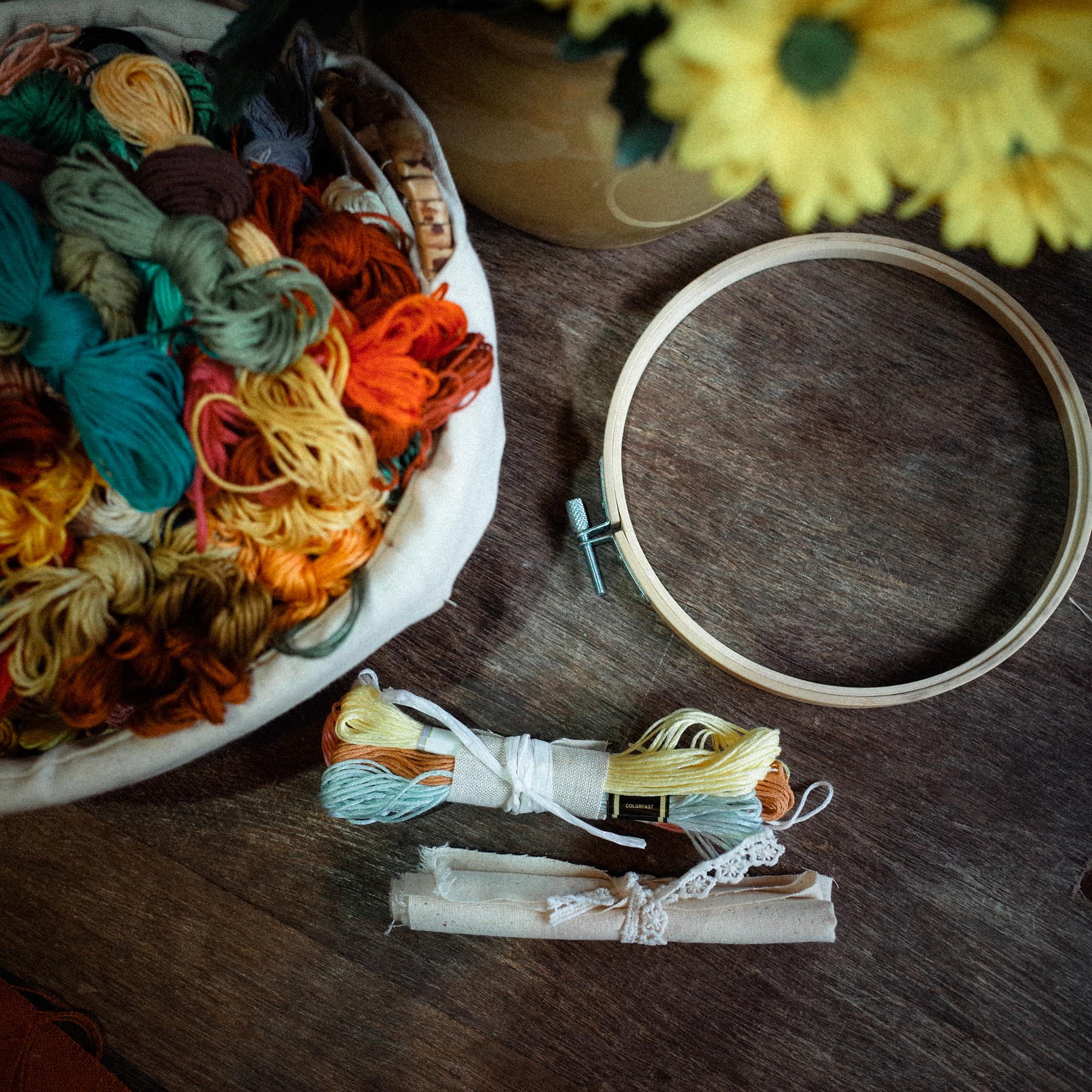 Studio table with threads, needles and partially finished embroidered hoop
