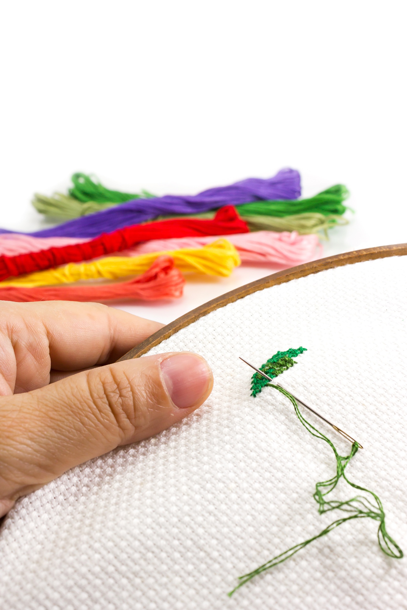 Workspace with hands embroidering a floral motif